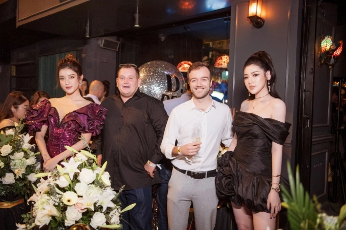 Huyền My (ngoài tùng bên trái) và Tú Anh (ngoài cùng bên phải) chụp ảnh cùng CEO Adam Christopher Chaplin (áo đen) và khách mời tại buổi tiệc.