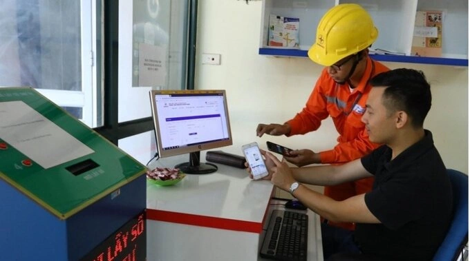 Nhân viên ngành Điện hướng dẫn khách hàng sử dụng dịch vụ điện trực tuyến. Ảnh: EVN