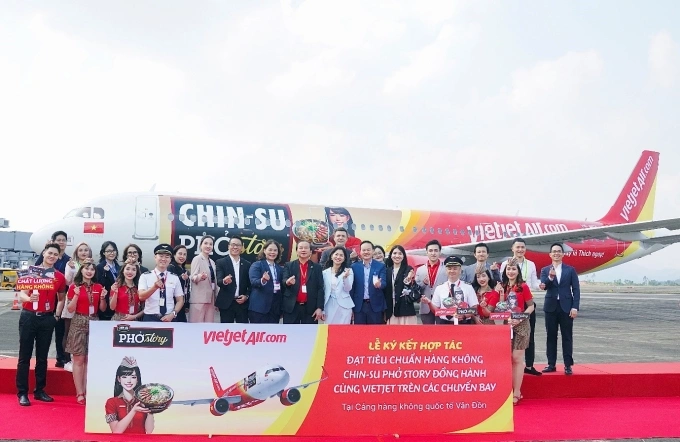 Các khách mời đến từ các bộ, ban ngành, đại diện Masan Consumer và Vietjet bên tàu bay mang hình ảnh Chin-Su Phở Story trên sân bay Vân Đồn, Quảng Ninh sáng 4/12. Ảnh: MSC