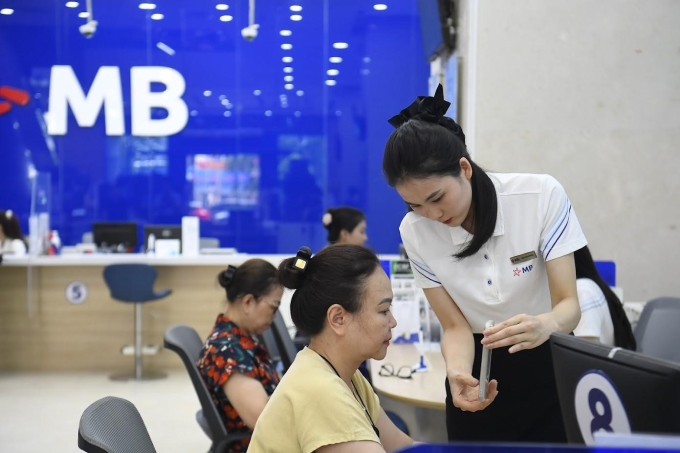 Nhân viên ngân hàng hướng dẫn khách thực hiện định danh sinh trắc học. Ảnh: MB