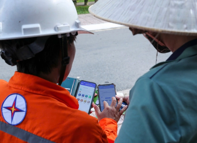 Nhân viên Tổng công ty hướng dẫn khách hàng cài đặt app CSKH để theo dõi trực tuyến. Ảnh: EVNSPC