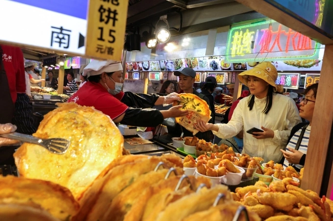 Khách hàng tại một quầy đồ ăn ở Thượng Hải (Trung Quốc), tháng 5/2025. Ảnh: Reuters