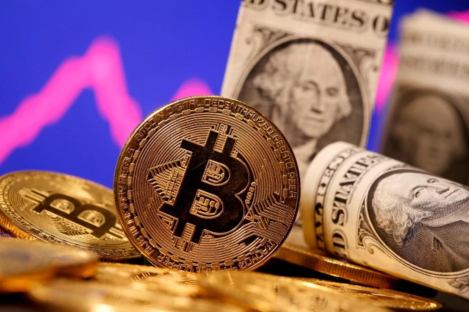 Biểu trưng của Bitcoin đặt cạnh các tờ đôla Mỹ. Ảnh: Reuters