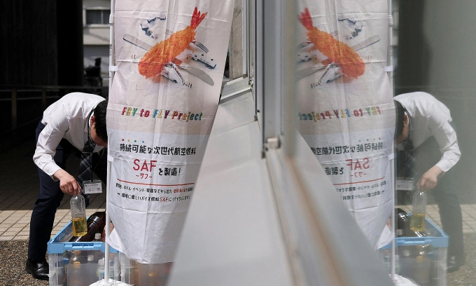 Một nhân viên công quyền giúp thu gom chai đựng dầu ăn sau sử dụng cho dự án Fry to Fly, tại quận Adachi, Tokyo, Nhật Bản, ngày 18/4. Ảnh: Reuters
